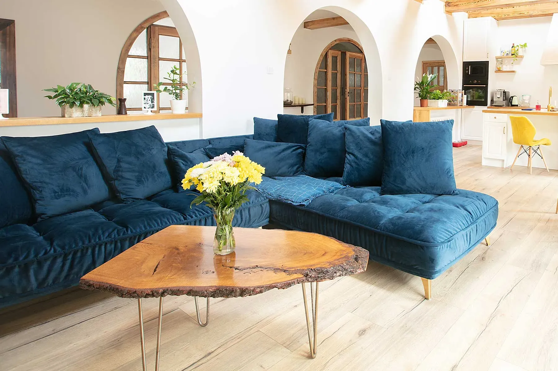 Tidy living room with a blue sectional and flowers on a wooden coffee table, illustrating rental cleaning services